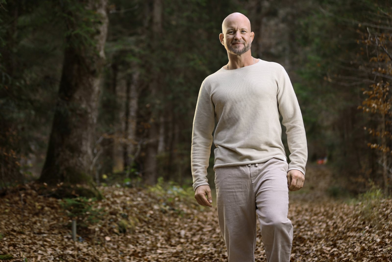 André Walberer geht lächelnd auf einem herbstlichen Waldweg – Kontakt für ein kostenloses Erstgespräch